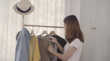 Evde dolap veya mağaza içinde onun moda kıyafet giysiler seçmek güzel çekici genç Asyalı kadın. Kız ne kazak giymeyi düşünüyorum. Ev dolap ya da soyunma giyim mağazası. 