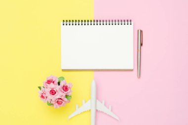 Seyahat etmek yaz kavramı - üstten görünüm mockup beyaz kağıt defter, kırtasiye, uçak ve pembe gül pembe ve sarı pastel renkli ekran üzerinde düz yatıyordu tasarımı. Yaz aylarında pastel renk arka plan üzerinde seyahat