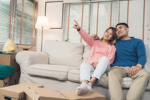 Sweet happy young Asian couple moving clothes and many objects from old home to their new home and relax on sofa in living room at their home. Lifestyle couple move new home.