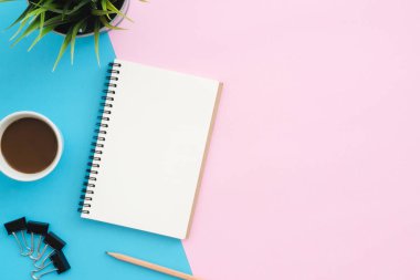 Yaratıcı düz Fotoğraf çalışma masası yatıyordu. Üstten görünüm ofis masası mavi pembe renkli arka plan üzerinde bitki, kalem, defter ve kahve Kupası ile. Kopya alanı, düz yatıyordu fotoğraf ile üstten görünüm.
