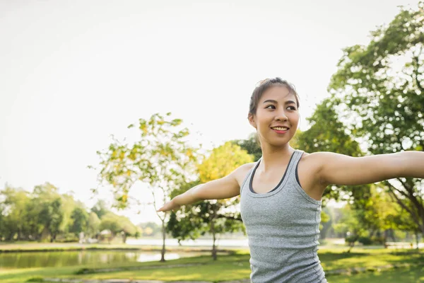 Young asian woman yoga outdoors keep calm and meditates while practicing yoga to explore the inner peace. Yoga have good benefits for health near lake at park. Sport and Healthy lifestyle concept.