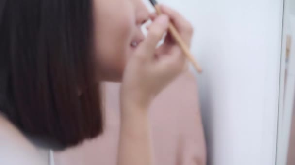 美丽的亚洲女人使用眼影化妆在前镜 快乐的女性使用美容化妆品 以提高自己准备在卧室在家里工作 生活方式的女性放松在家里的概念 — 图库视频影像