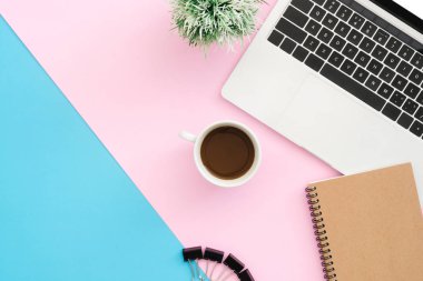 Yaratıcı düz Fotoğraf çalışma masası yatıyordu. Üstten görünüm ofis büro dizüstü bilgisayar, klip, defter, kahve fincanı ve bitki mavi pembe renkli arka plan üzerinde. Kopya alanı, düz yatıyordu fotoğraf ile üstten görünüm.