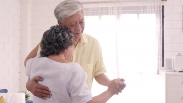 亚洲的一对老年夫妇在客厅里一边跳舞一边听音乐 甜蜜的夫妇在家里放松的时候一边享受爱情的时刻 生活方式老年人家庭在家里放松一下 — 图库视频影像