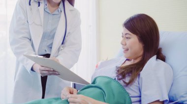 Güzel akıllı Asyalı doktor ve tartışmak ve Pano Doktor elinde bir şeyler olurken, hastanın yatakta Hastanesi'nde açıklayan hasta. Tıp ve sağlık kavramı.