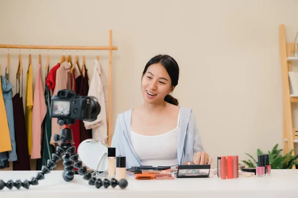 Beauty blogger present beauty cosmetics sitting in front camera for recording video. Beautiful asian woman use cosmetics review make up tutorial broadcast live video to social network by internet.