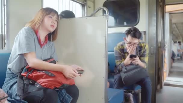 旅行者亚洲妇女使用智能手机听音乐放松 而坐火车 年轻的女游客背包客享受她的旅程在泰国 生活方式青少年妇女放松和旅行的概念 — 图库视频影像