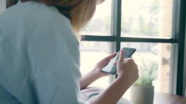 Kafede masada otururken konuşma, okuma ve manifatura için Smartphone kullanarak iş serbest Asyalı kadın. Kahve dükkanı concepts çalışma yaşam tarzı zeki güzel kadınlar.