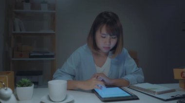 Güzel akıllı Asya genç girişimci iş kadın sahibi KOBİ online ürün stok kontrol ve gece eve geç çalışma tablet kaydedin. Küçük işletme sahibi, ev ofis kavramı.
