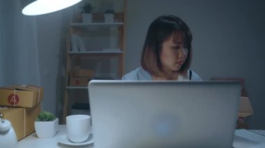 Güzel akıllı Asya genç girişimci iş kadın sahibi KOBİ online ürün stok kontrol ve gece eve geç çalışan bilgisayara kaydedin. Küçük işletme sahibi, ev ofis kavramı.