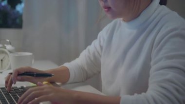 Genç Asyalı kadın dizüstü bilgisayar üzerinde geç çalışıyor ve evde oturma odasında kahve içiyor. Asya iş kadını çalışma belge finans ve hesap makinesi gece evde ofis. Evde vakit geçirmenin keyfini çıkarın.