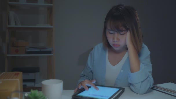 若いアジアの起業家のビジネス女性の所有者は 在庫の製品をチェックし 自宅で夜に働いてタブレットに保存します 気分が悪くて疲れている ホームオフィスコンセプトのスモールビジネスオーナー — ストック動画