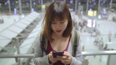 Kullanarak ve uçağının kalkış kapısı uluslararası havaalanında beklerken onun smartphone terminal salonunda kontrol mutlu Asyalı kadın. Kadınlar Havaalanı kavramında mutlu.