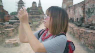 Ayutthaya tatil gezisi geçirirken bir fotoğraf çekmek için akıllı telefon kullanarak Gezgin Asyalı kadın, Tayland, kadın geleneksel şehirde inanılmaz dönüm noktasında yolculuğuntadını çıkarın. 