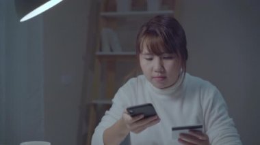 Evde gece oturma odasında masada oturma rahat giymek ederken kredi kartı ile online alışveriş satın smartphone kullanarak güzel Asyalı kadın. Ev ofis kavramı çalışan Lifestyle kadınlar.