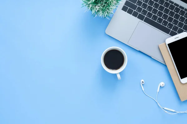 Office desk working space - Flat lay top view mockup photo of working space with laptop, smartphone, coffee up and notebook on blue pastel background. Pastel blue color background working desk concept