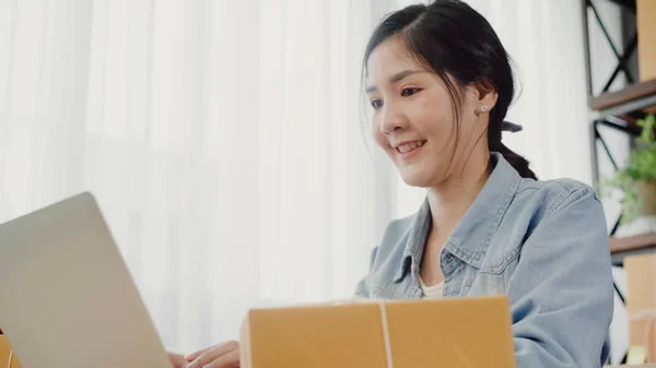 Vakker smart asiatisk ung entreprenør, forretningskvinne, eier av SMB-er, online som sjekker produkter på aksjer, og sparer til datamaskin som arbeider hjemme. Småbedriftseier på hjemmekontor . – stockfoto