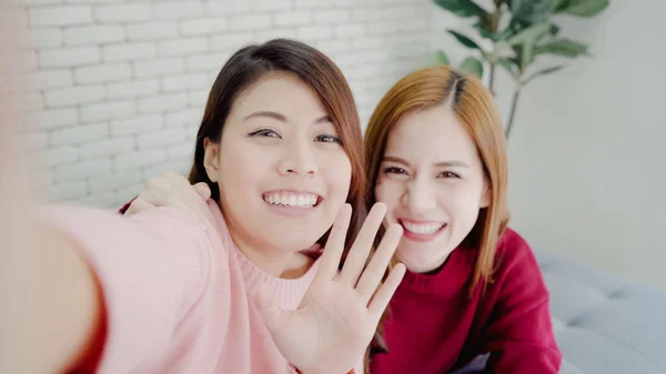 Las mujeres blogueras asiáticas usando selfie de teléfonos inteligentes y grabando video vlog en la sala de estar en casa, grupo de amigos disfrutan de momentos divertidos mientras están tumbadas en el sofá cuando se relajan en casa. Punto de vista . —  Fotos de Stock