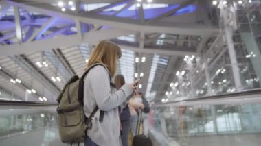 Kullanarak ve uçağının kalkış kapısı uluslararası havaalanında beklerken onun smartphone terminal salonunda kontrol mutlu Asyalı kadın. Kadınlar Havaalanı kavramında mutlu.