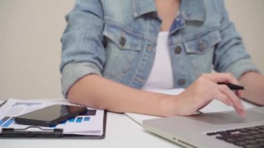 Asyalı kadın çalışma dizüstü evde oturma odasında masa üzerinde gülümseyen güzel genç. Asya iş kadını defter belge finans ve hesap makinesi ev ofis yazma. Ev concept anda zevk.