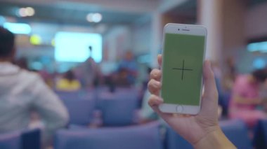 Asyalı kadın uçağının kalkış kapısı uluslararası havaalanında beklerken terminal salonunda yeşil ekran beyaz hareket eden telefon aygıt kullanarak. Kadınlar Havaalanı kavramında mutlu. Chroma anahtar.