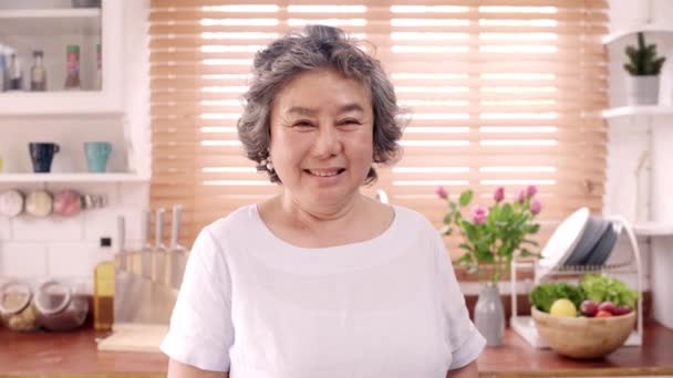 亚洲老妇人感到快乐的微笑和看着相机 而放松在厨房在家里 生活方式 高级女性家庭概念 — 图库视频影像