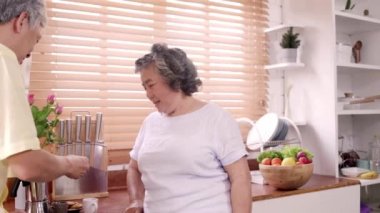 Asyalı yaşlı çift evde mutfakta kahvaltı yapıyor. Çinli tatlı çift adam evde karısına kurabiye yediriyor. Evde yaşam tarzı üst düzey aile kavramı.