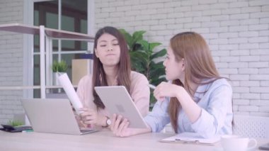 Birlikte bir rapor ya da memnun gülümsüyor ve başarılı ekip çalışması ile evrak gönüllülük onların küçük iş oturma, bir ofiste çalışan iki genç Asyalı kadınlar. İş, teknoloji ve office kavramı.