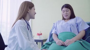 Konuşma ve el kadın hasta için hasta yatağında tutan genç Asyalı doktor kadın. Tıp, yaş, sağlık, psikiyatrist ve insanlar kavramı.