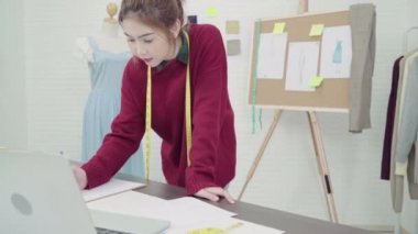 Profesyonel güzel Asyalı kadın moda kumaş çizimler ile çalışma ve dizüstü bilgisayar kullanarak tasarımcı çizim giyim tasarım stüdyoda bul. Yaşam tarzı kadın kavramı çalışma.