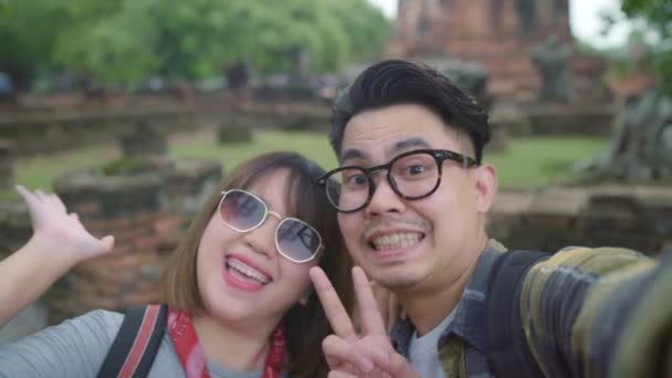 アユタヤ タイでの休暇旅行を過ごしながら Selfie を取ってスマート フォンを使用して旅行アジア カップル カップル伝統的な都市の素晴らしいランドマークで彼らの旅をお楽しみください — ストック動画