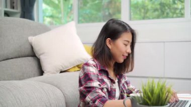 Genç iş serbest Asyalı kadın çalışma ödev masanın üstünde laptop ne zaman evde oturma odasında rahatlayın. Yaşam tarzı latin ve İspanyol etnisite kadın evde çalışma kavramı.