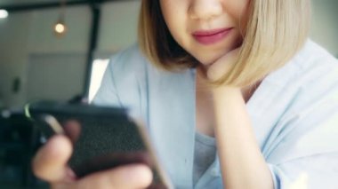 Kafede masada otururken konuşma, okuma ve manifatura için Smartphone kullanarak iş serbest Asyalı kadın. Kahve dükkanı concepts çalışma yaşam tarzı zeki güzel kadınlar.