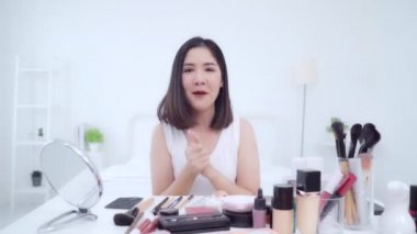 Güzellik blogger video kayıt için kamera önünde oturan güzellik kozmetik mevcut. Asyalı kadın kullanım kozmetik inceleme yapmak öğretici mutlu güzel genç sosyal ağ için canlı video yayını.
