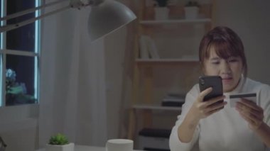Evde gece oturma odasında masada oturma rahat giymek ederken kredi kartı ile online alışveriş satın smartphone kullanarak güzel Asyalı kadın. Ev ofis kavramı çalışan Lifestyle kadınlar.