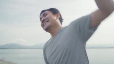 Isınma ve germe kollarını sokak, sağlıklı genç erkek egzersiz yakın göl üzerinde çalıştırmak için hazır için Asya runner man bacaklar. Yaşam tarzı uygun ve etkin erkekler sokak kavramı üzerinde egzersiz.