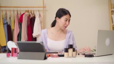 Güzellik blogger soru ve cevap-laptop önünde oturan video kayıt için tablet. Asyalı kadın kullanım kozmetik inceleme yapmak öğretici mutlu güzel genç sosyal ağ için canlı video yayını