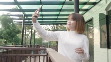 Bangkok, Tayland şehir merkezinde seyahat ederken selfie alarak akıllı telefon kullanarak Neşeli güzel genç Asya backpacker blogger kadın. Yaşam çantası turist seyahat tatil konsepti.