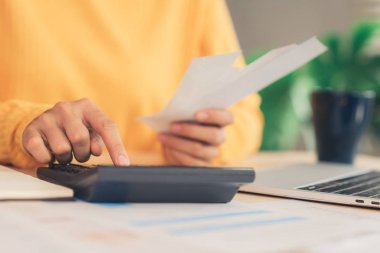 Asyalı kadın çalışma dizüstü evde oturma odasında masa üzerinde gülümseyen güzel genç. Asya iş kadını defter belge finans ve hesap makinesi ev ofis yazma. Ev concept anda zevk.