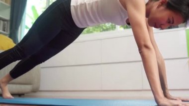 Genç Asyalı kadın oturma odasında yoga yapıyor. Çekici, güzel bir kadın evde sağlıklı bir yaşam için çalışıyor. Yaşam tarzı kadın egzersiz konsepti.