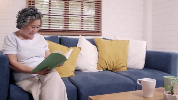 Азиатская Пожилая Женщина Читает Книгу Гостиной Дома Китаянка Лежит Диване — стоковое видео