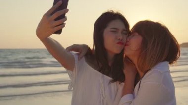 Genç Asyalı lezbiyen çift plaj yakın selfie alarak Smartphone kullanarak. Güzel kadınlar LGBT çift Happy Relax akşam gün batımı aşk anı keyfini çıkarın. Lifestyle lezbiyen çift seyahat üzerinde plaj kavramı
