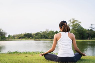 Genç Asyalı kadın yoga açık havada sakin olun ve iç barış keşfetmek için yoga uygulamak ise derin derin düşünür. Yoga lake Park yakınındaki sağlık için iyi faydaları vardır. Spor ve sağlıklı yaşam konsepti.