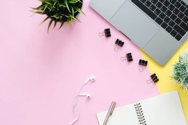 Yaratıcı düz fotoğraf çalışma masası yatıyordu. Üstten Görünüm ofis büro dizüstü bilgisayar ve boş boş defter pastel pembe sarı renk arka plan üzerinde. Kopya alanı, düz yatıyordu fotoğraf ile Üstten Görünüm.