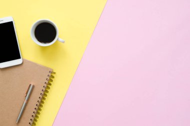 Ofis Masası adlı kullanıcının alanı - düz çalışma beyaz boş defter sayfası, kahve fincanı ve sahte telefon pastel arka plan üzerinde bir çalışma alanının en iyi görünümü yatırın. Pastel pembe sarı renk arka plan boşluk kavramı.