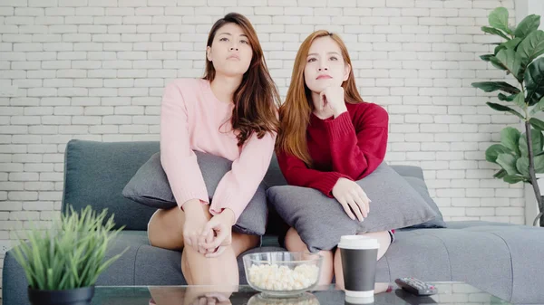 Couple asiatique lesbienne regarder la télévision rire et manger du pop-corn dans le salon à la maison, couple doux profiter moment amusant tout en étant allongé sur le canapé lorsqu'il est détendu à la maison. Mode de vie couple se détendre à la maison concept . — Photo