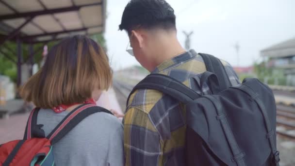 亚洲背包夫妇在火车站 年轻甜夫妇旅游背包客使用手机查找和方向地图 他们在泰国的旅程 生活方式夫妇放松和旅行概念 — 图库视频影像