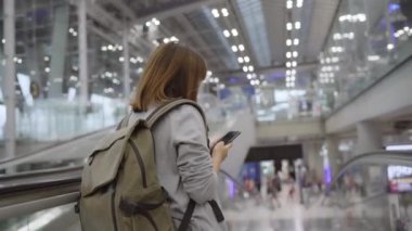 Kullanarak ve uçağının kalkış kapısı uluslararası havaalanında beklerken onun smartphone terminal salonunda kontrol mutlu Asyalı kadın. Kadınlar Havaalanı kavramında mutlu.
