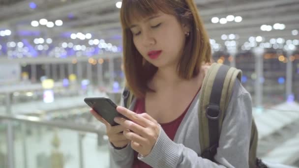 Glückliche Asiatin Die Ihr Smartphone Der Terminalhalle Benutzt Und Eincheckt — Stockvideo