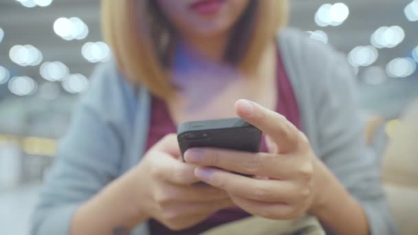 Счастливая Азиатская Женщина Использует Проверяет Свой Смартфон Сидя Стуле Зале — стоковое видео